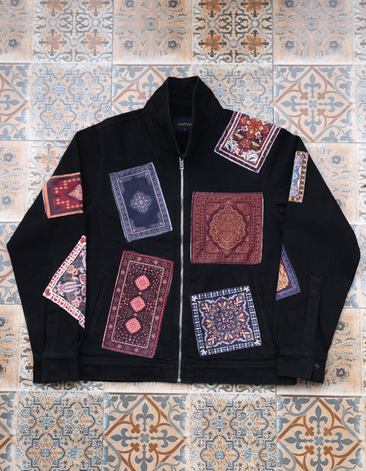 Black jacket with patterned patches on a tiled floor background