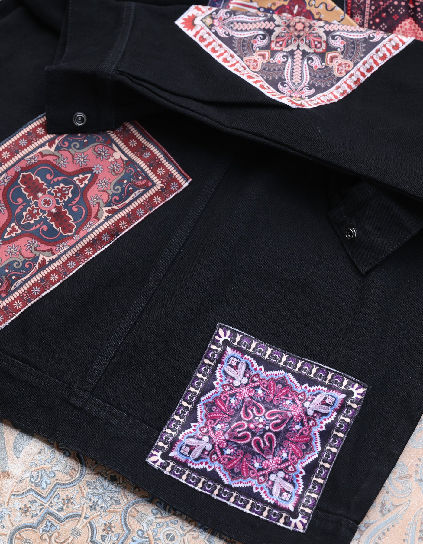 Black jacket with colorful paisley patterns on a patterned fabric background