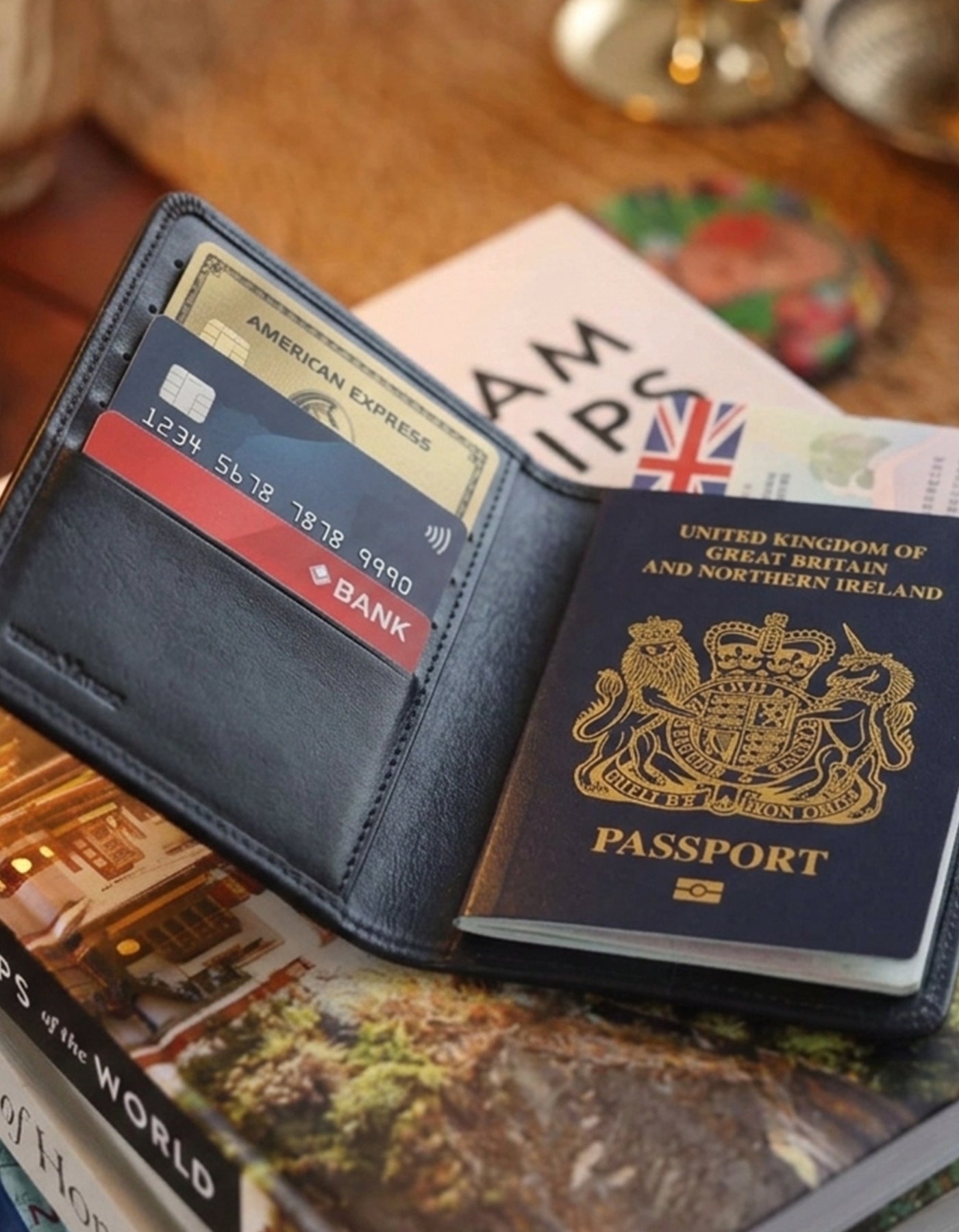 Open navy blue wallet with passport, American Express card, and travel guidebooks on a wooden surface.