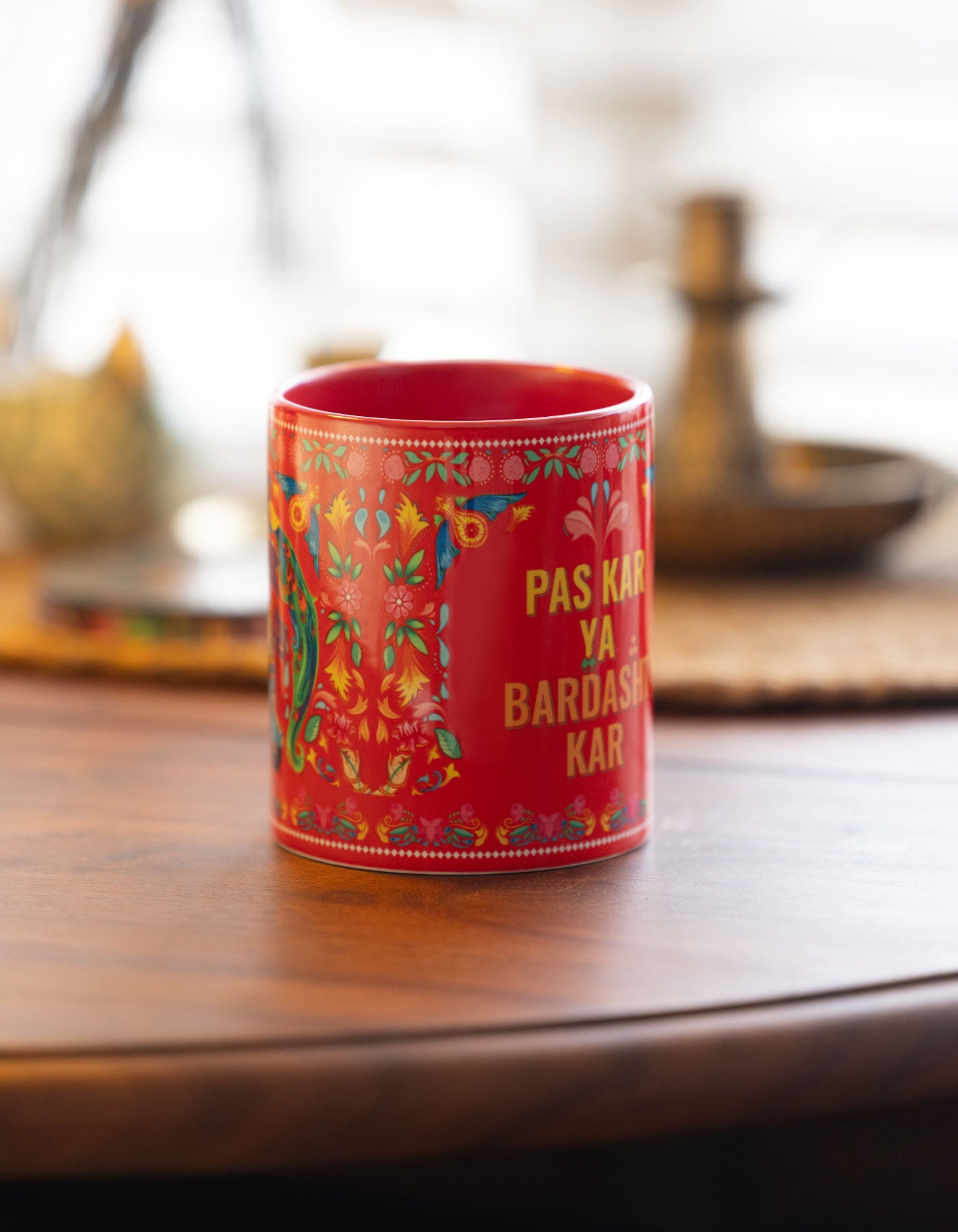 Red mug with colorful patterns and text on a wooden table