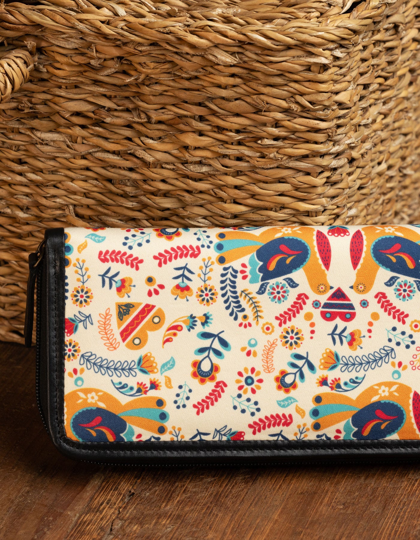 Colorful patterned wallet on a wooden surface with a woven basket in the background