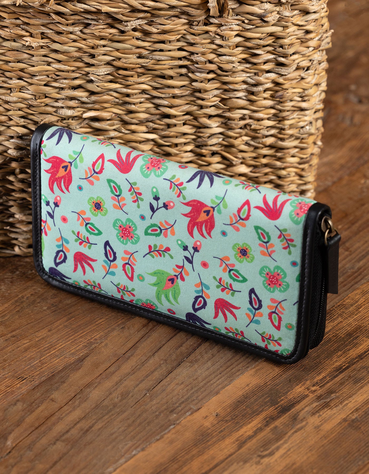 Floral patterned wallet on a wooden surface with a woven basket in the background