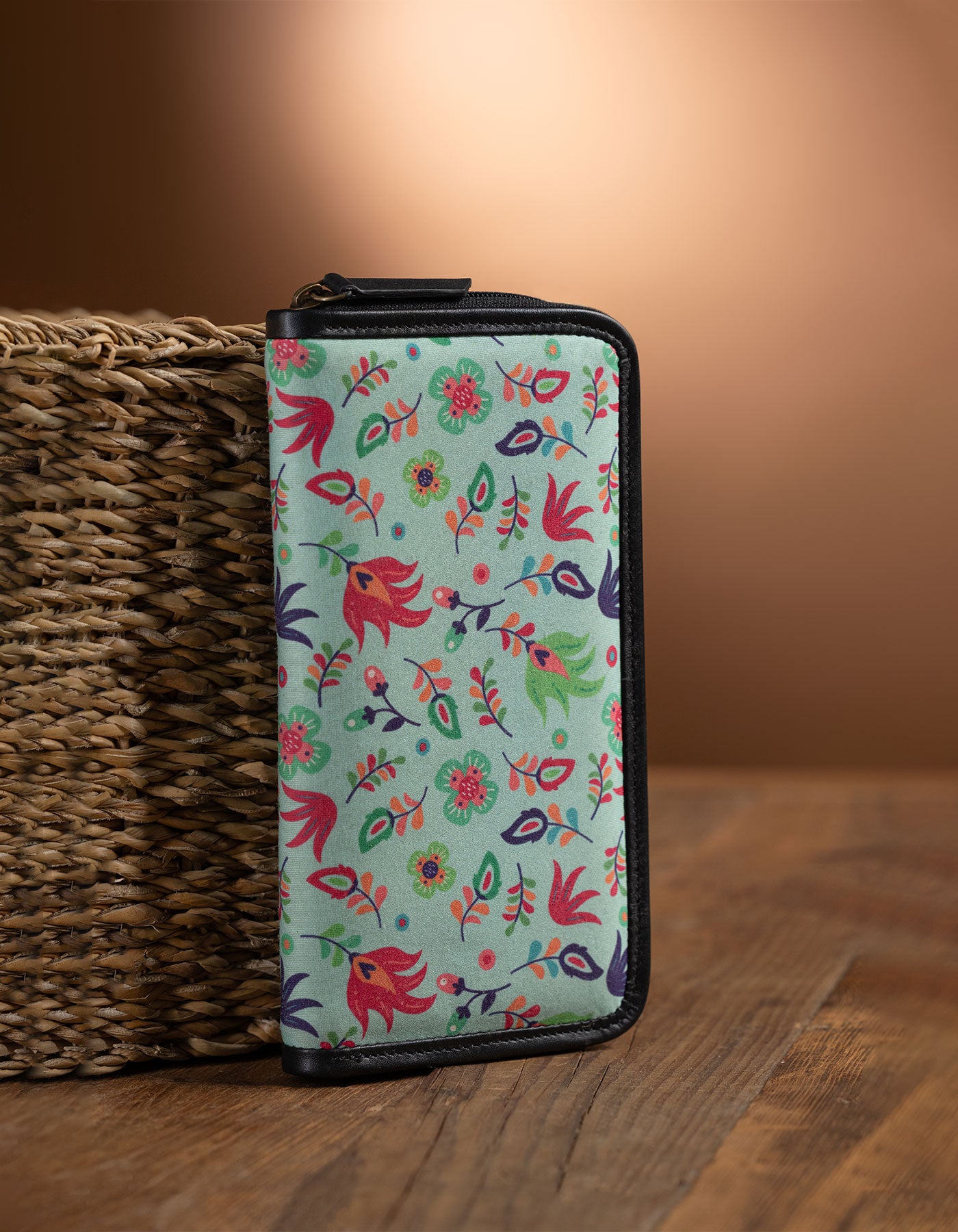 Floral-patterned wallet on a wooden surface with a woven basket