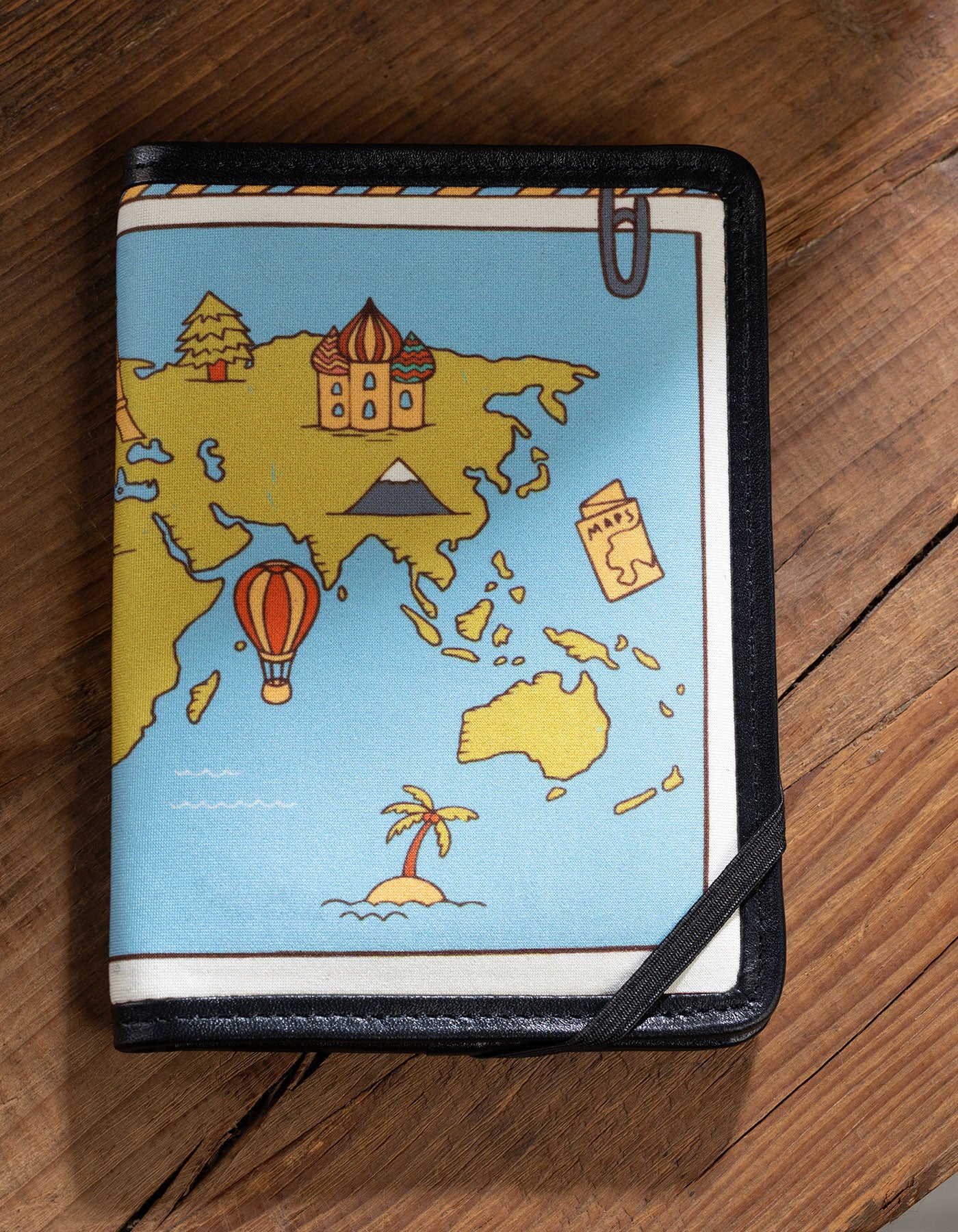 Notebook cover with world map design on a wooden surface