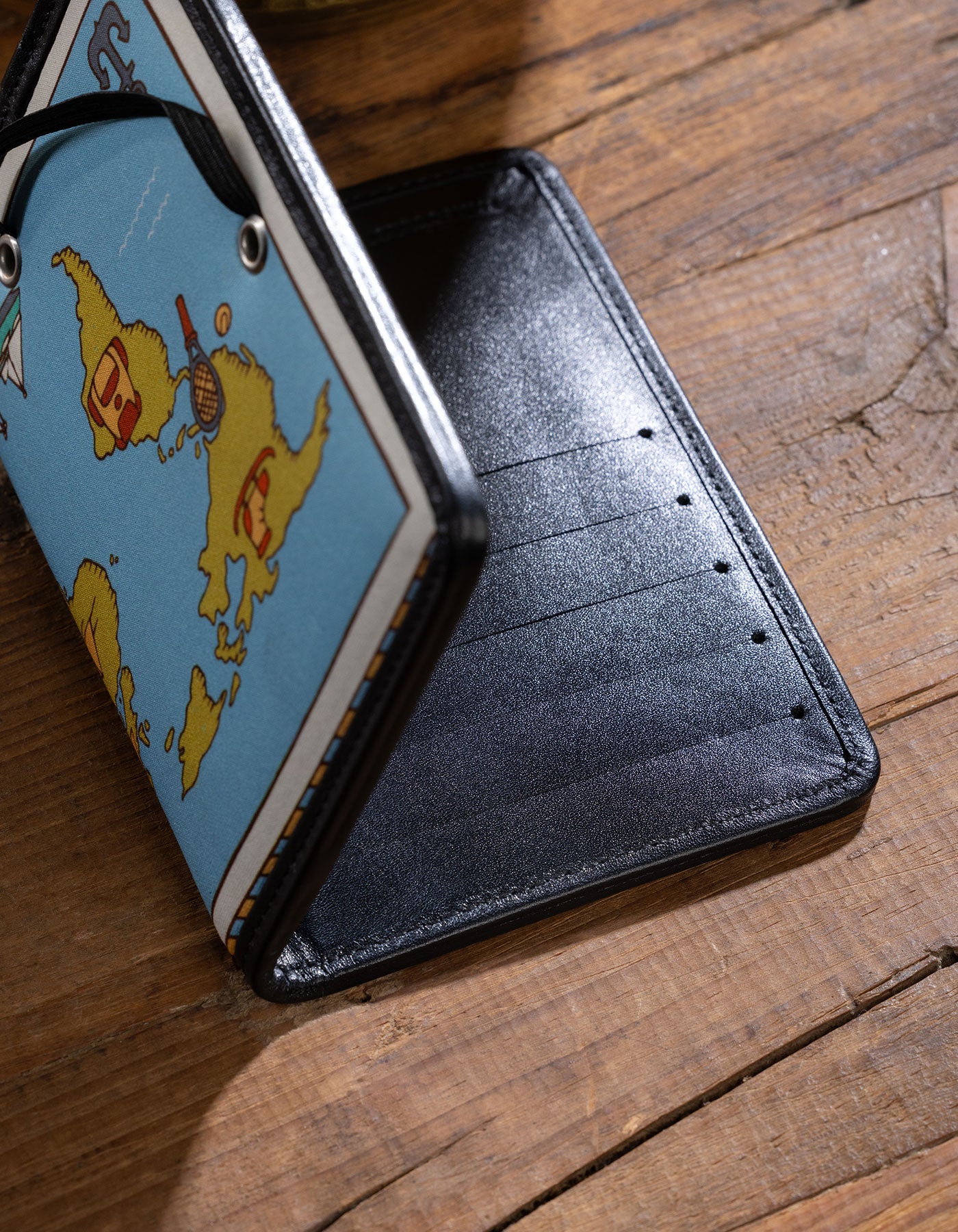 Black wallet with a map design on a wooden surface