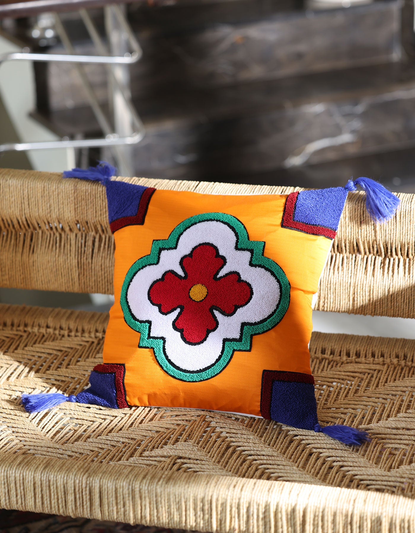 Decorative pillow with a colorful flower design on a wicker chair.