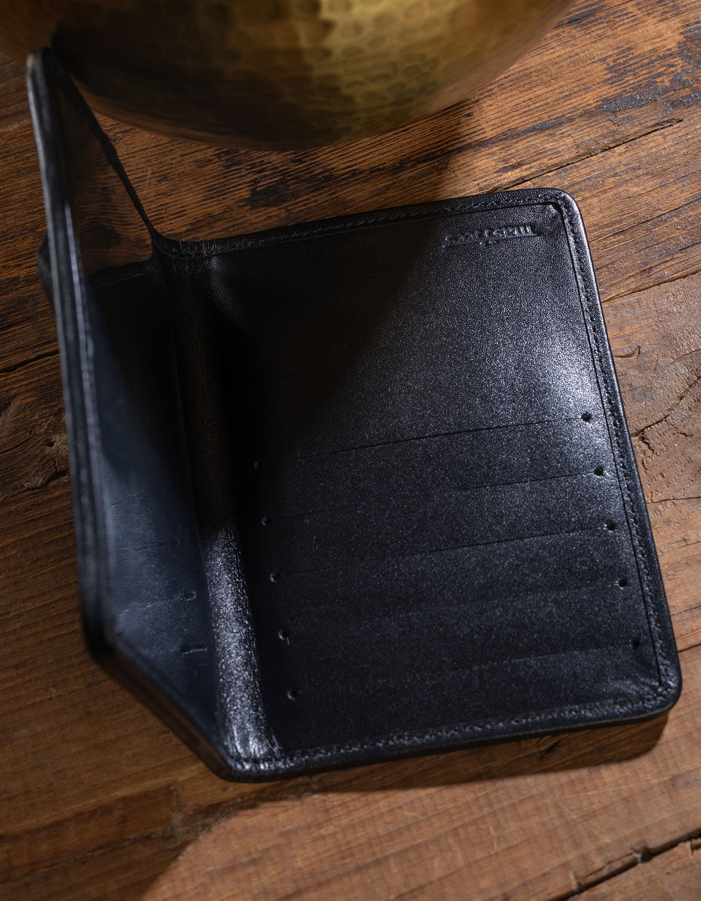 Black leather wallet on a wooden surface