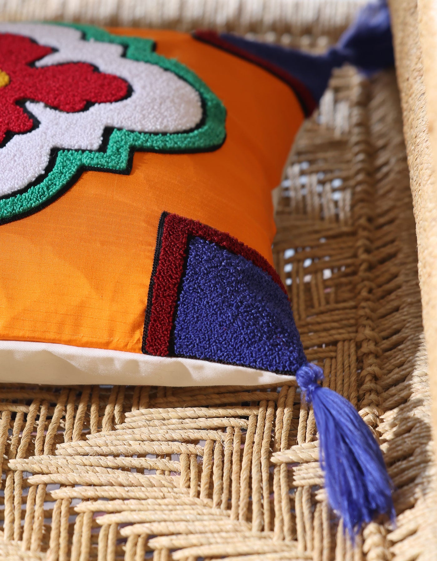 Colorful pillow with floral design and tassel on a woven surface
