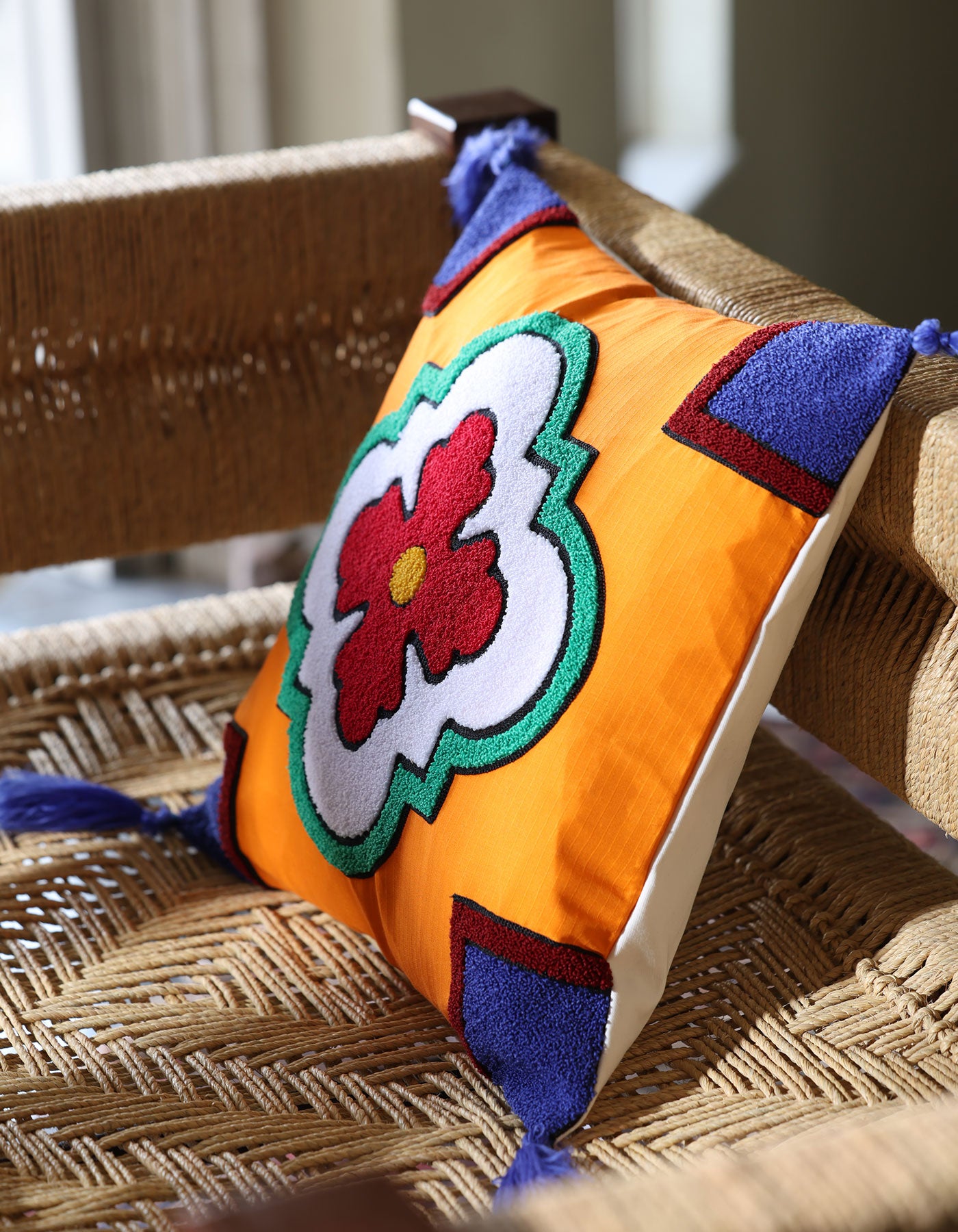 Decorative pillow with a colorful flower design on a woven chair