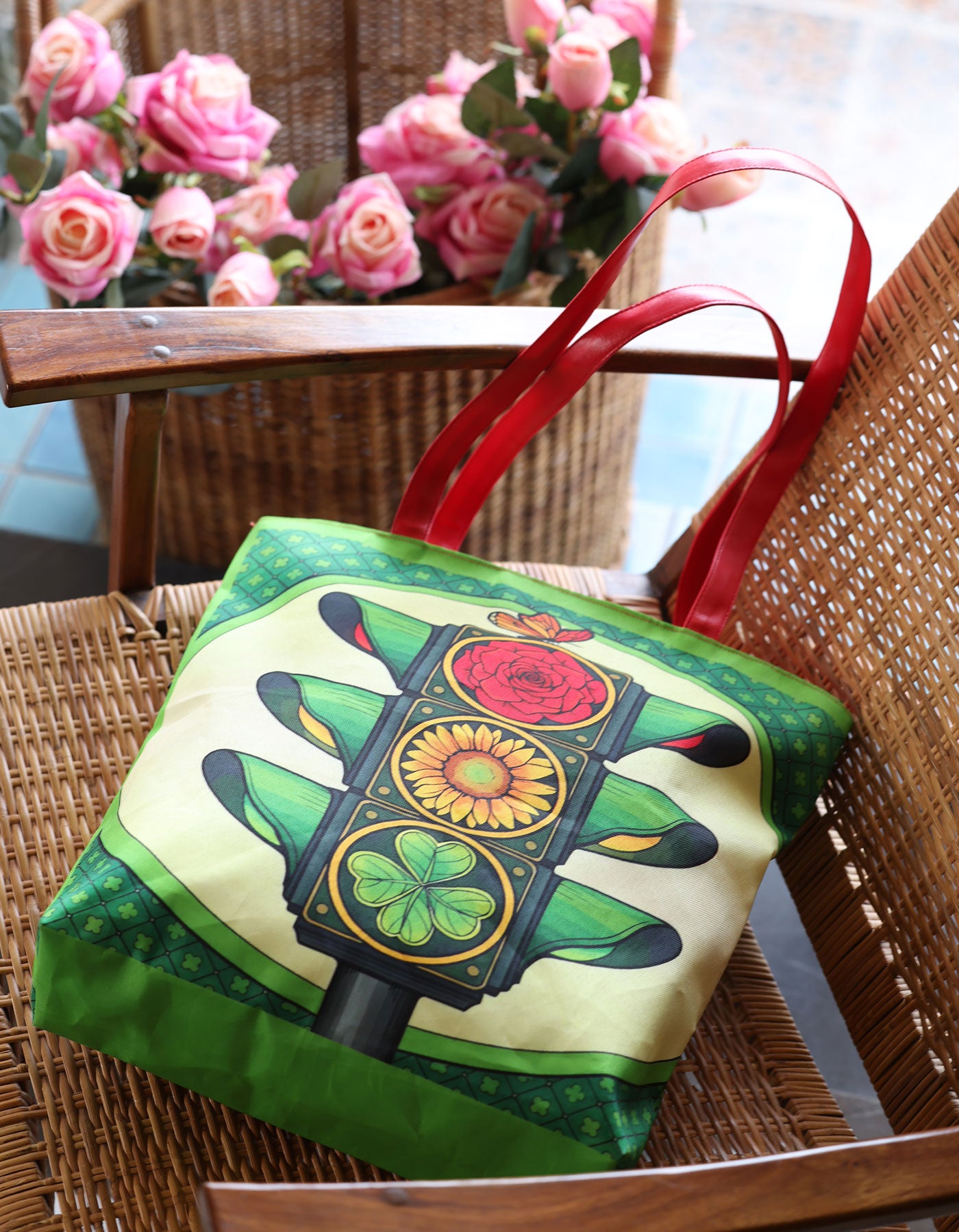 Green bag with traffic light design on a wicker chair with pink flowers in the background