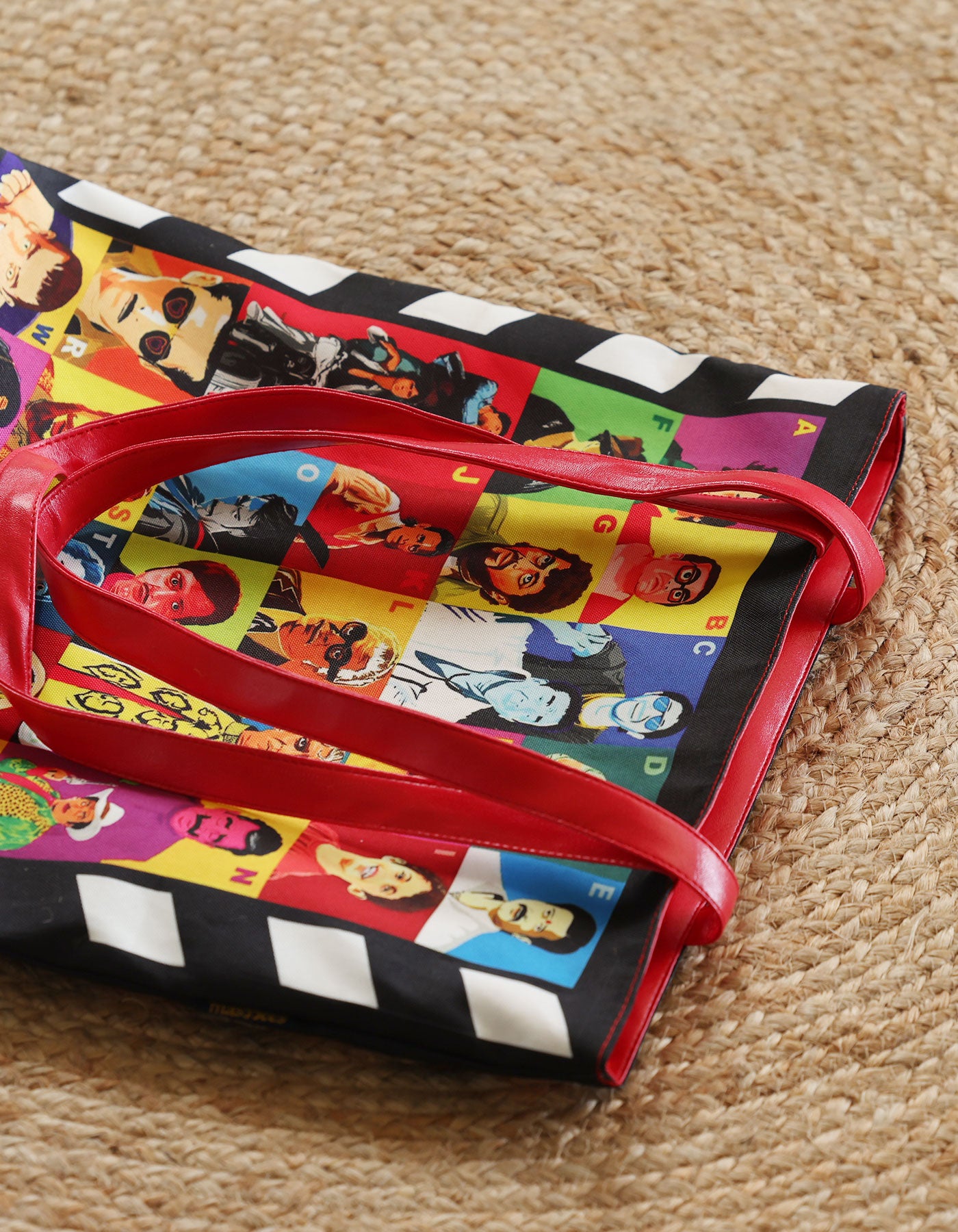 Colorful bag with character prints and red handle on a textured surface