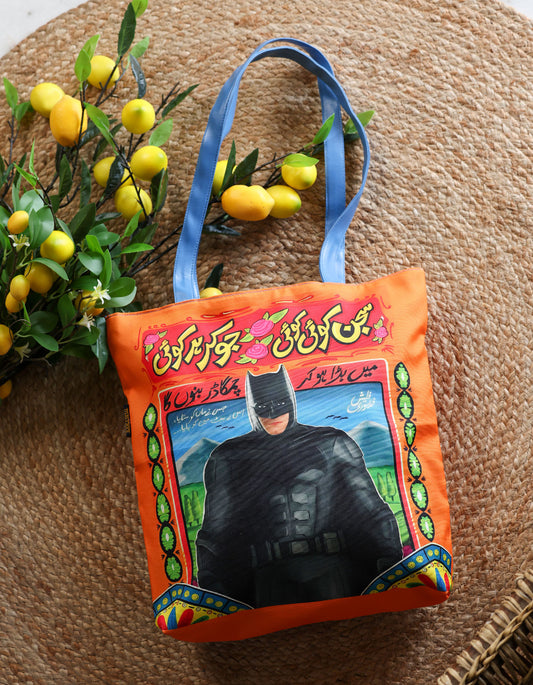 Colorful bag with a Batman design on a textured surface with lemons and leaves.