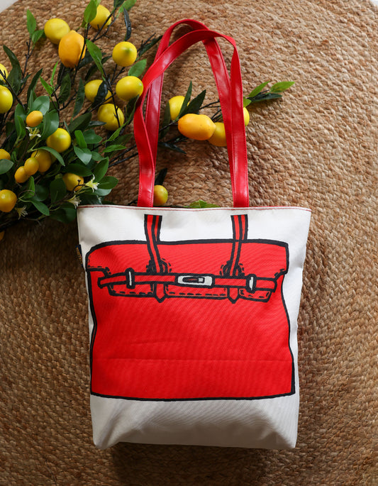 Tote bag with red handle and red handbag design on a textured surface with lemons and leaves.