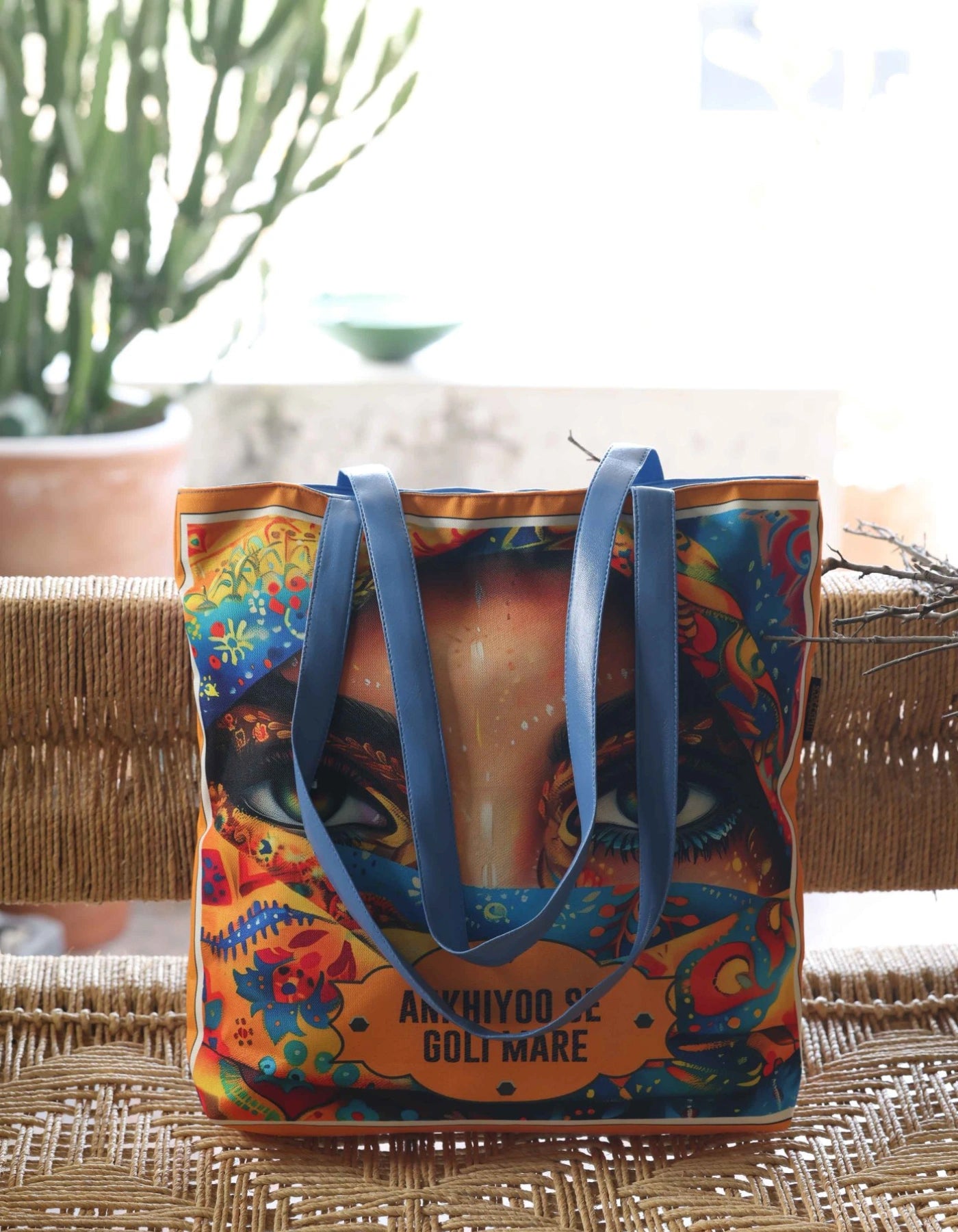 Colorful tote bag with blue handles on a woven surface