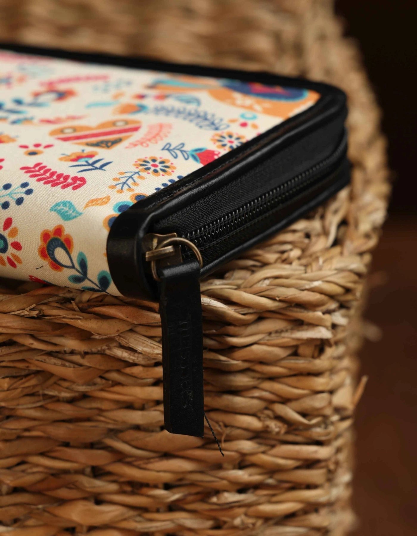Colorful floral-patterned pouch with a black zipper on a woven surface
