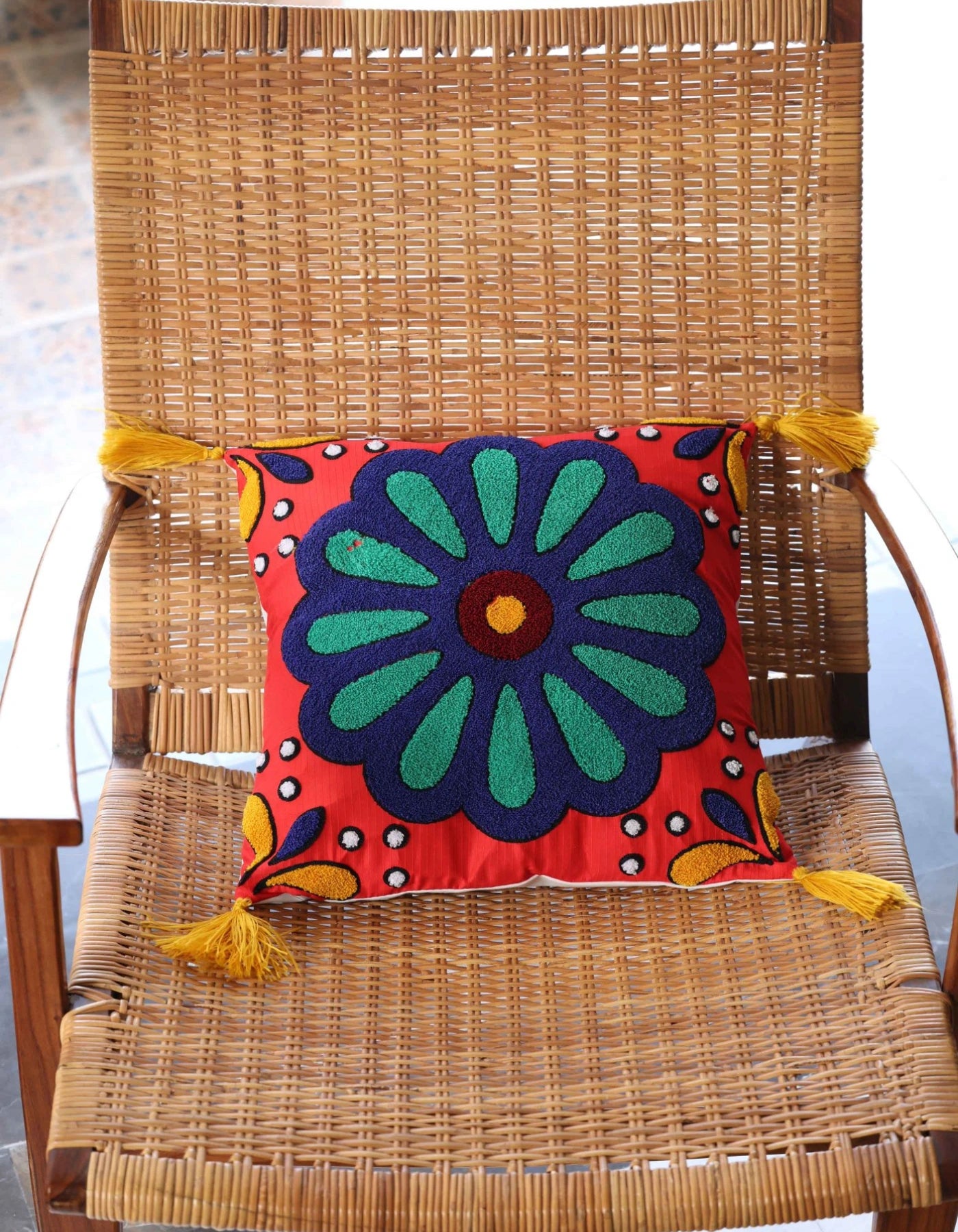 Colorful floral pillow with tassels on a wicker chair