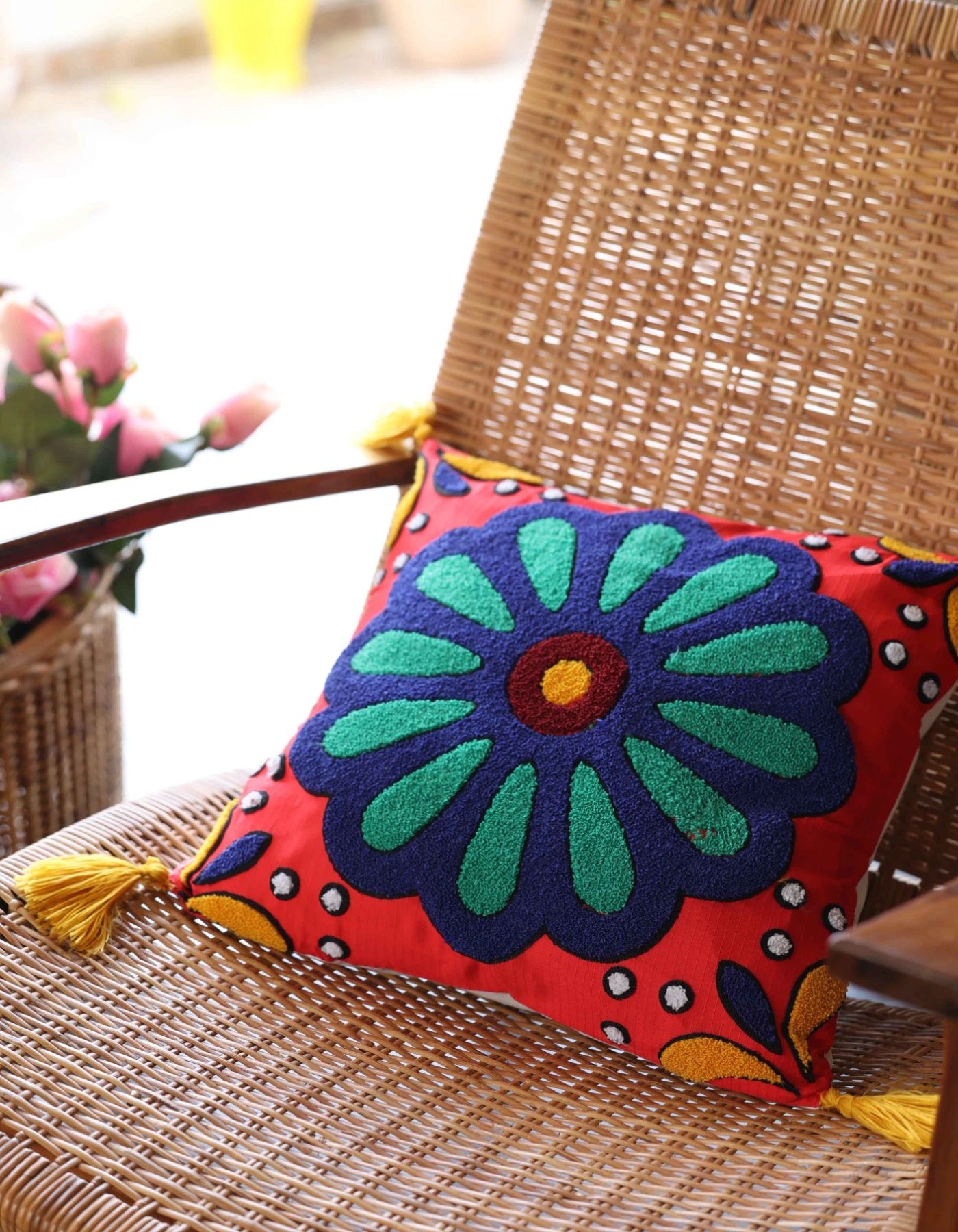Colorful floral pillow with tassels on a wicker chair