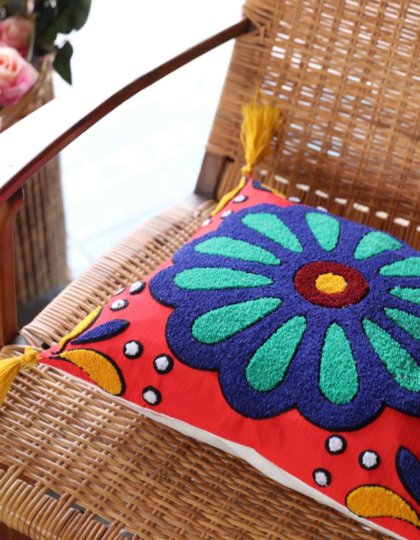 Colorful embroidered pillow on a wicker chair
