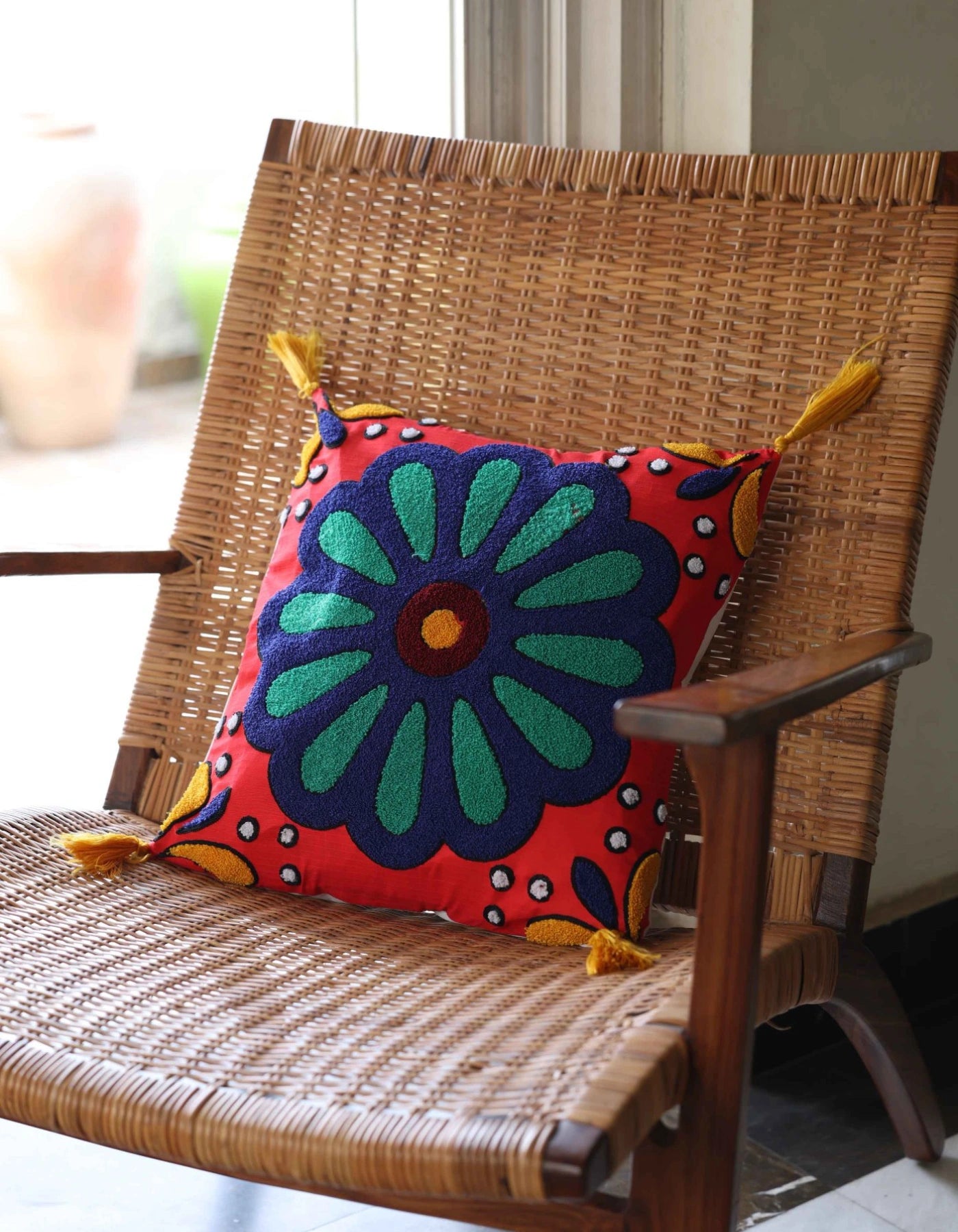 Decorative pillow with a colorful floral pattern on a wicker chair.