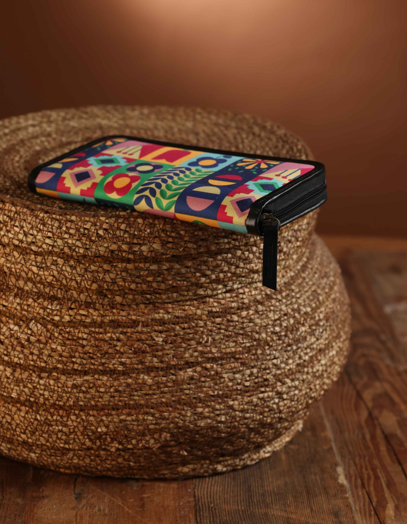 Phone case with colorful geometric pattern on a woven brown stool.
