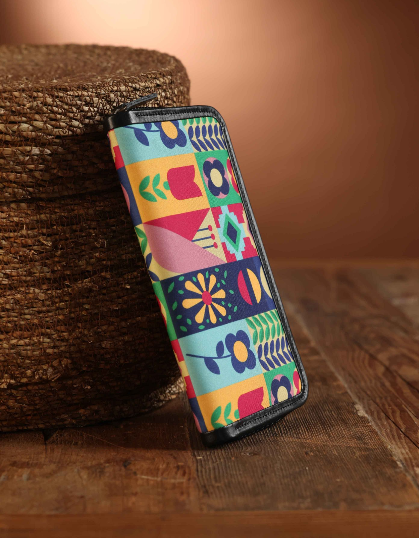 Colorful patterned wallet on a wooden surface with a woven basket in the background