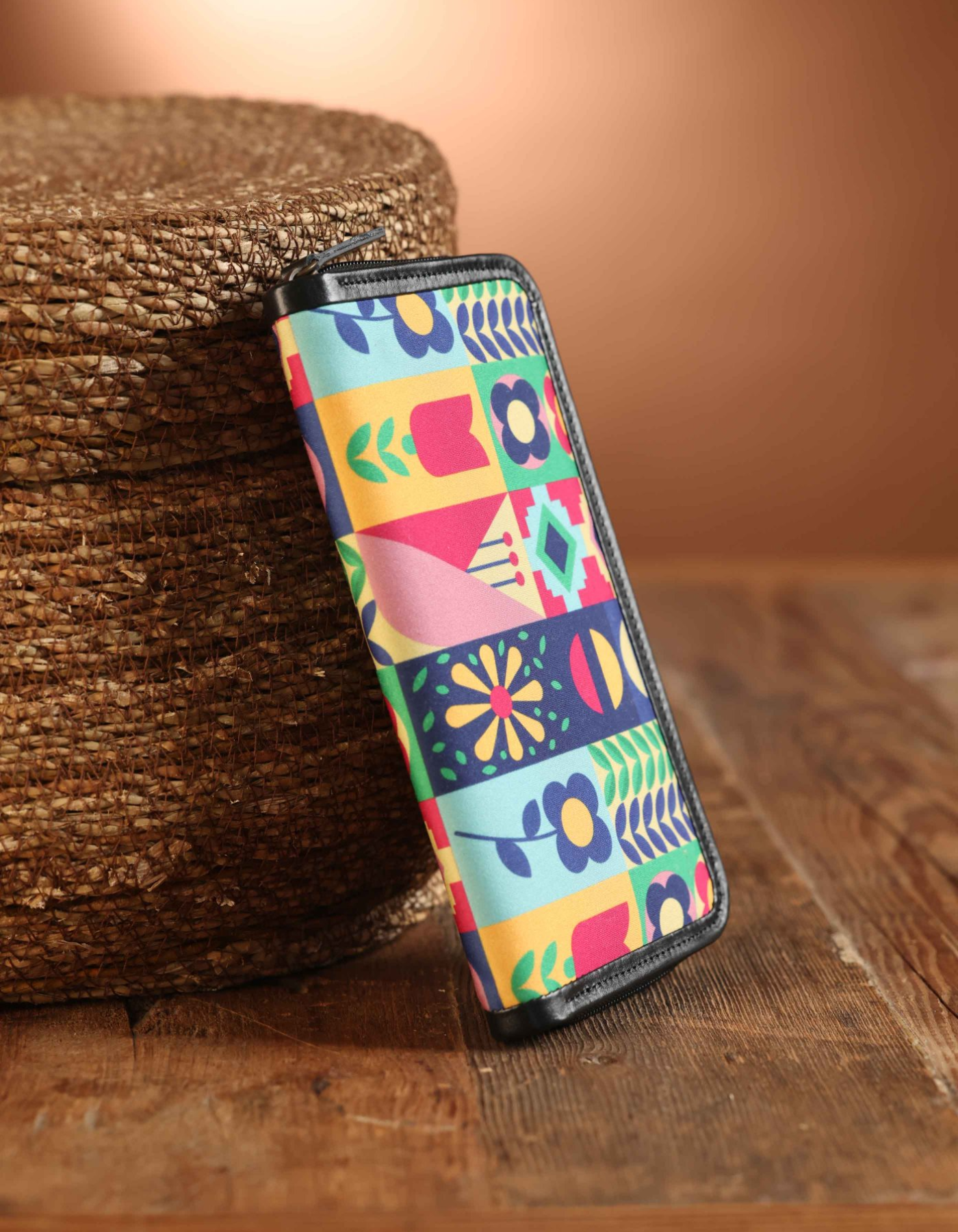 Colorful patterned pouch on a wooden surface with a woven basket in the background
