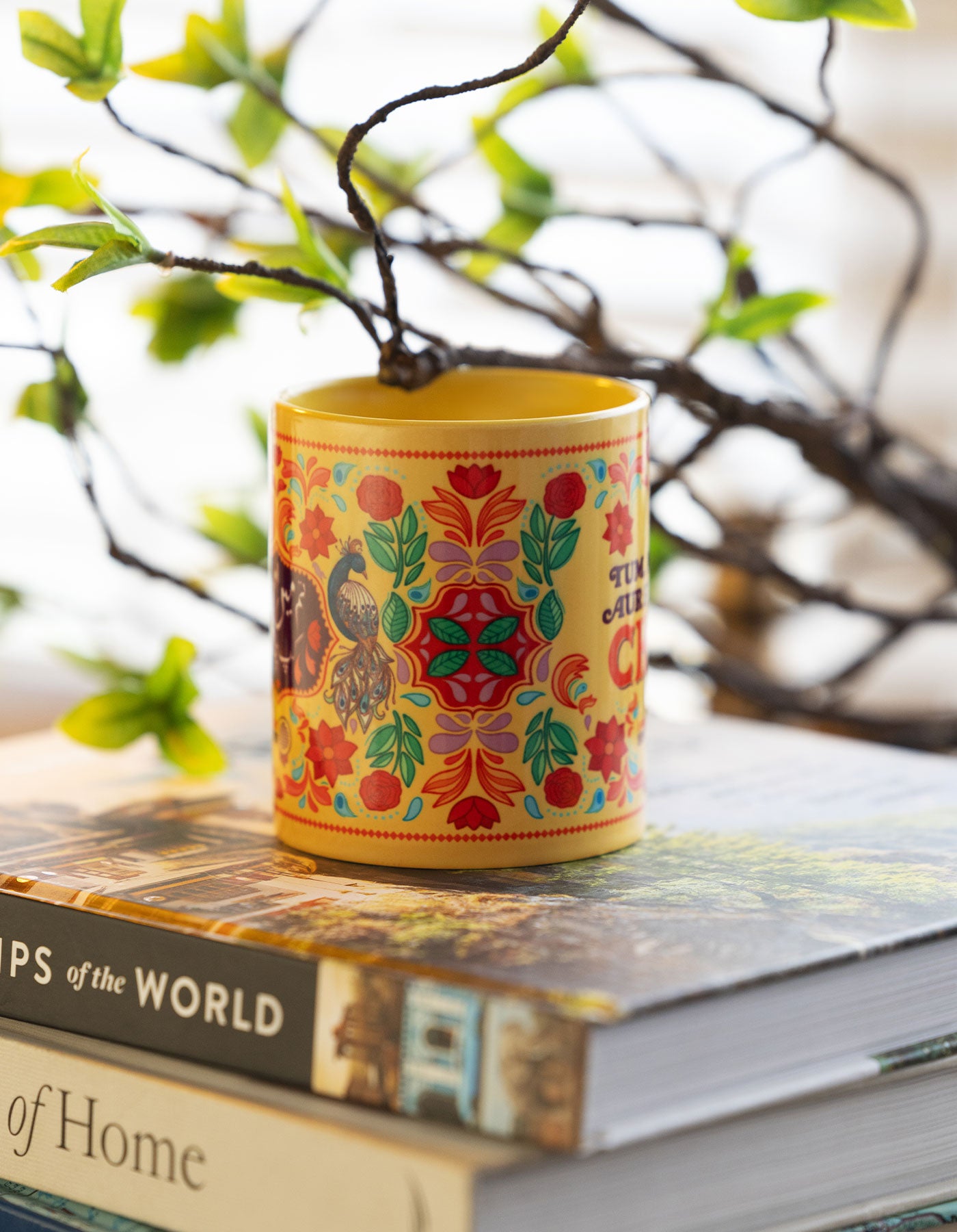 Colorful decoration on a Mug above stack of books with a blurred natural background