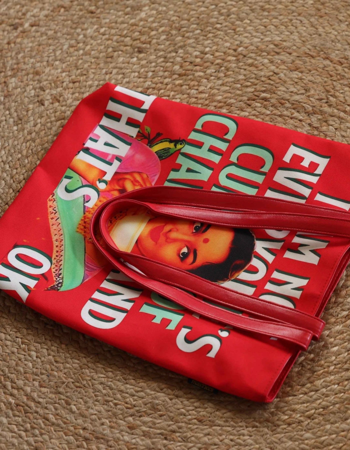 Red bag with colorful text and graphics on a beige carpet