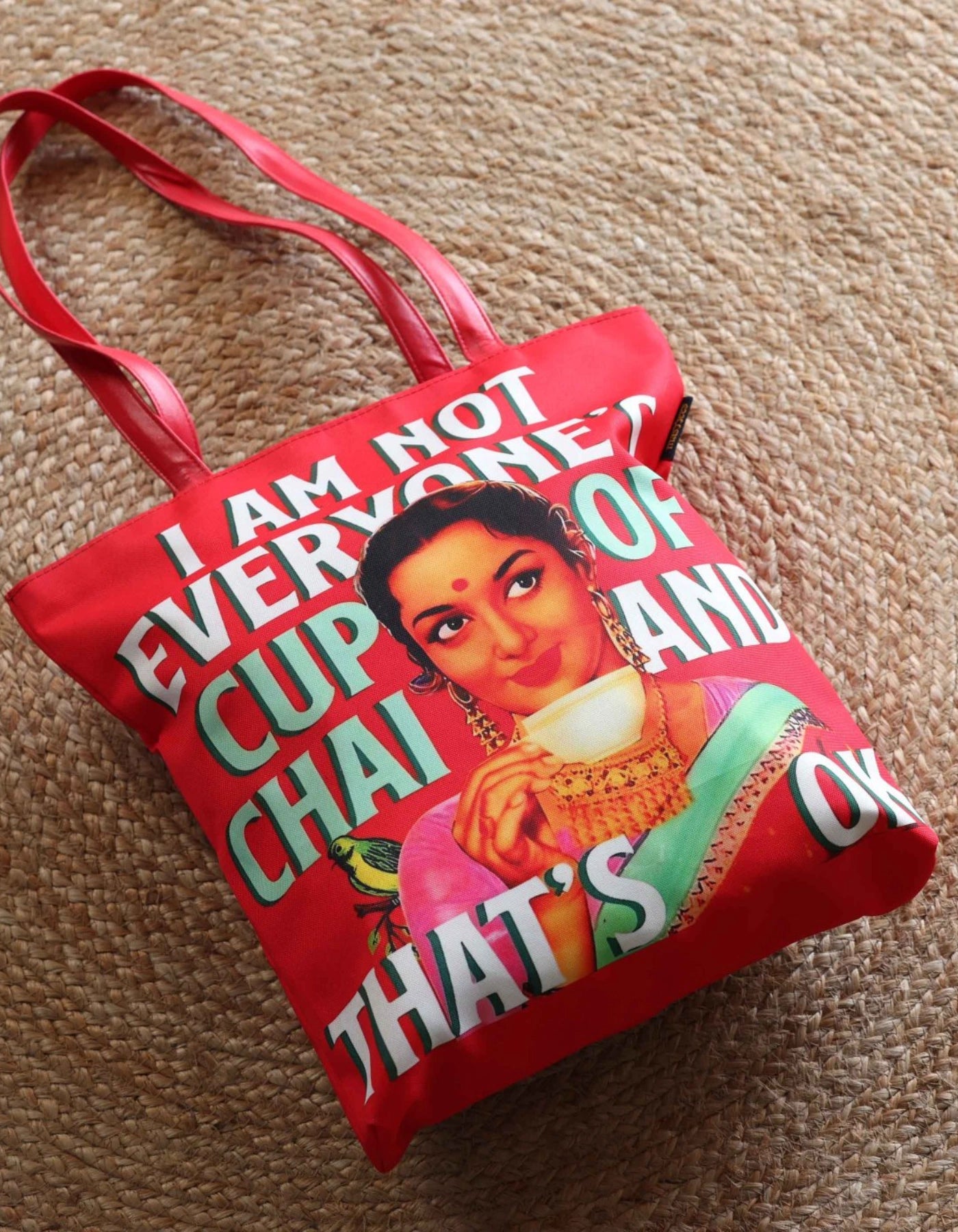 Red tote bag with a graphic design and text on a textured surface