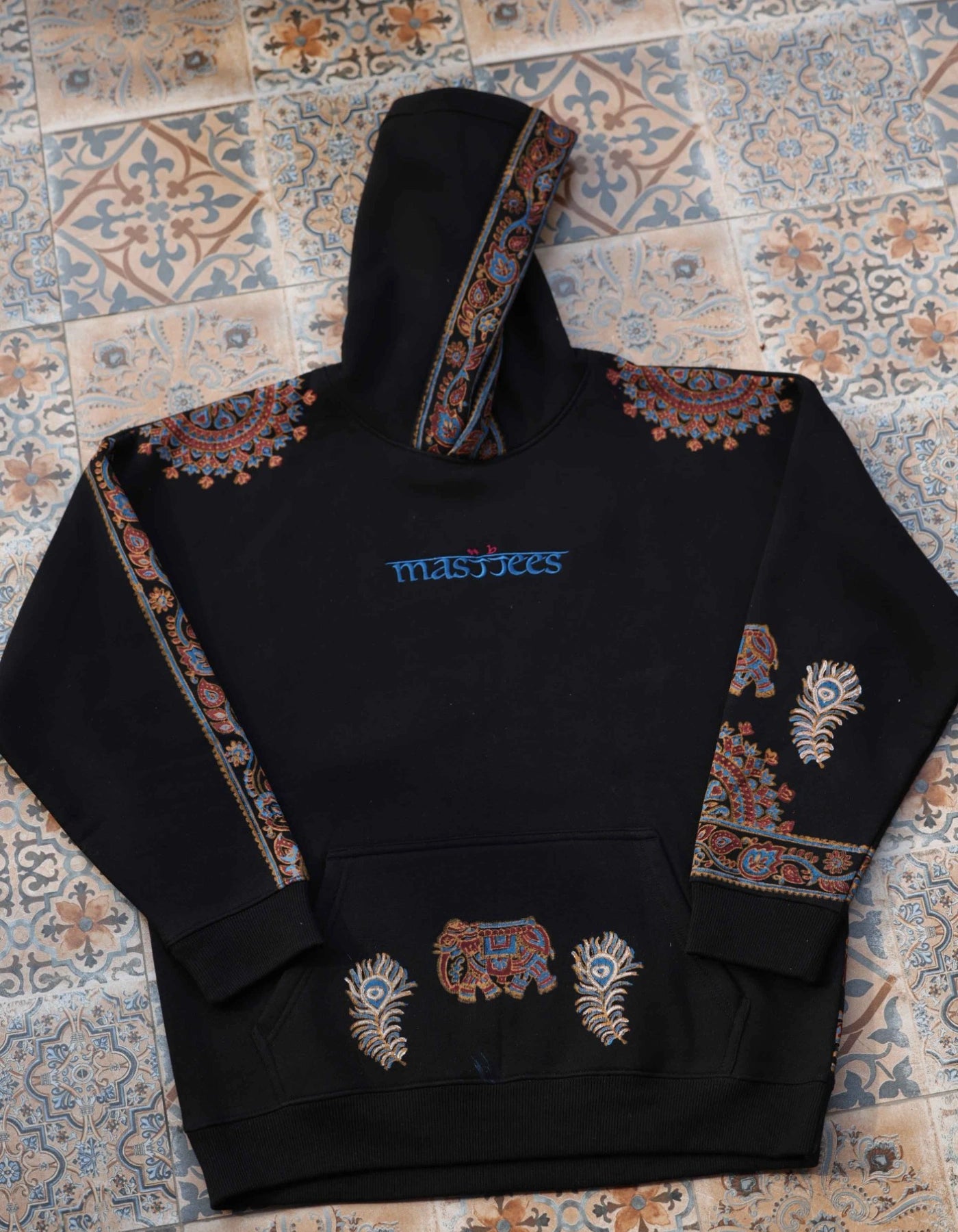 Black hoodie with colorful patterns on a patterned rug