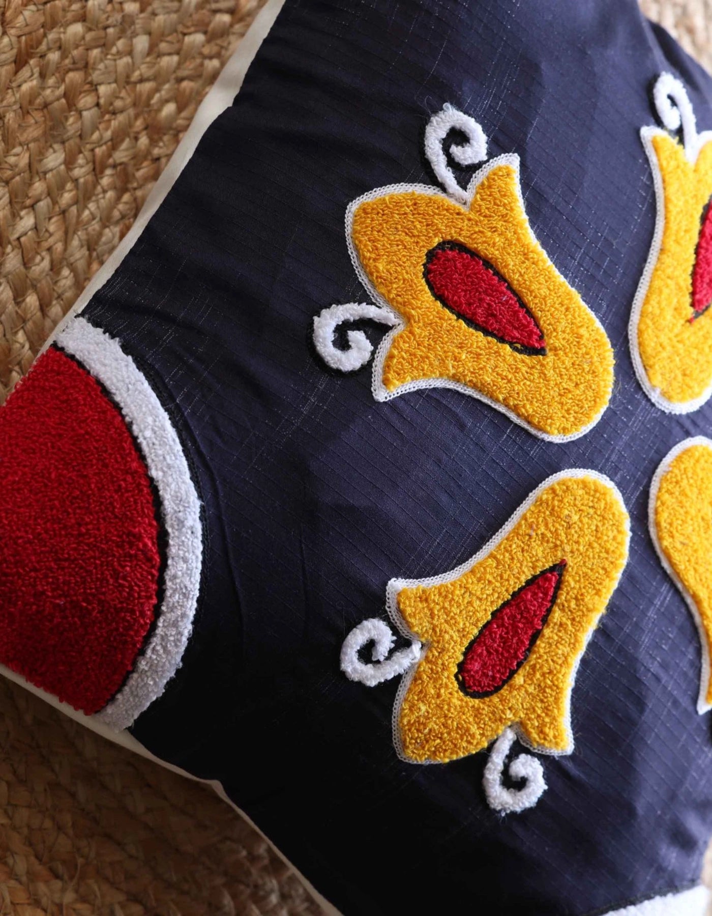 Navy blue fabric with yellow and red embroidered designs on a textured surface