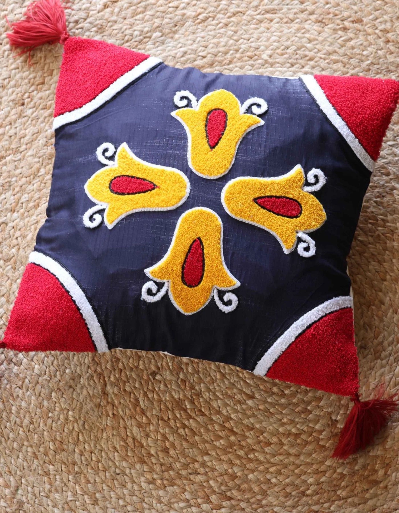 Decorative pillow with red, yellow, and blue patterns on a beige carpet