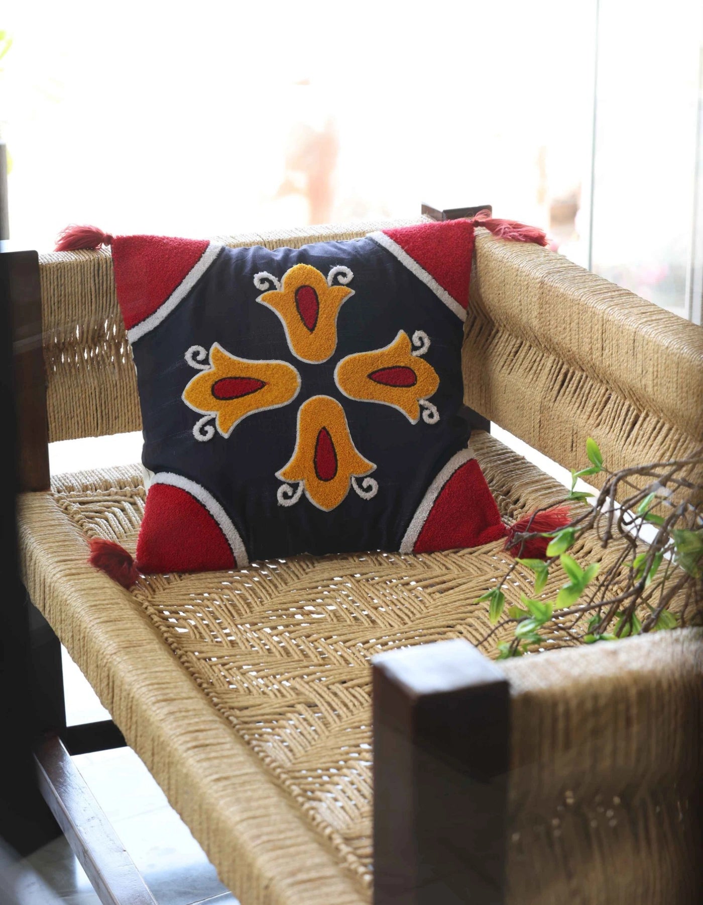 Decorative pillow with a colorful pattern on a woven chair.