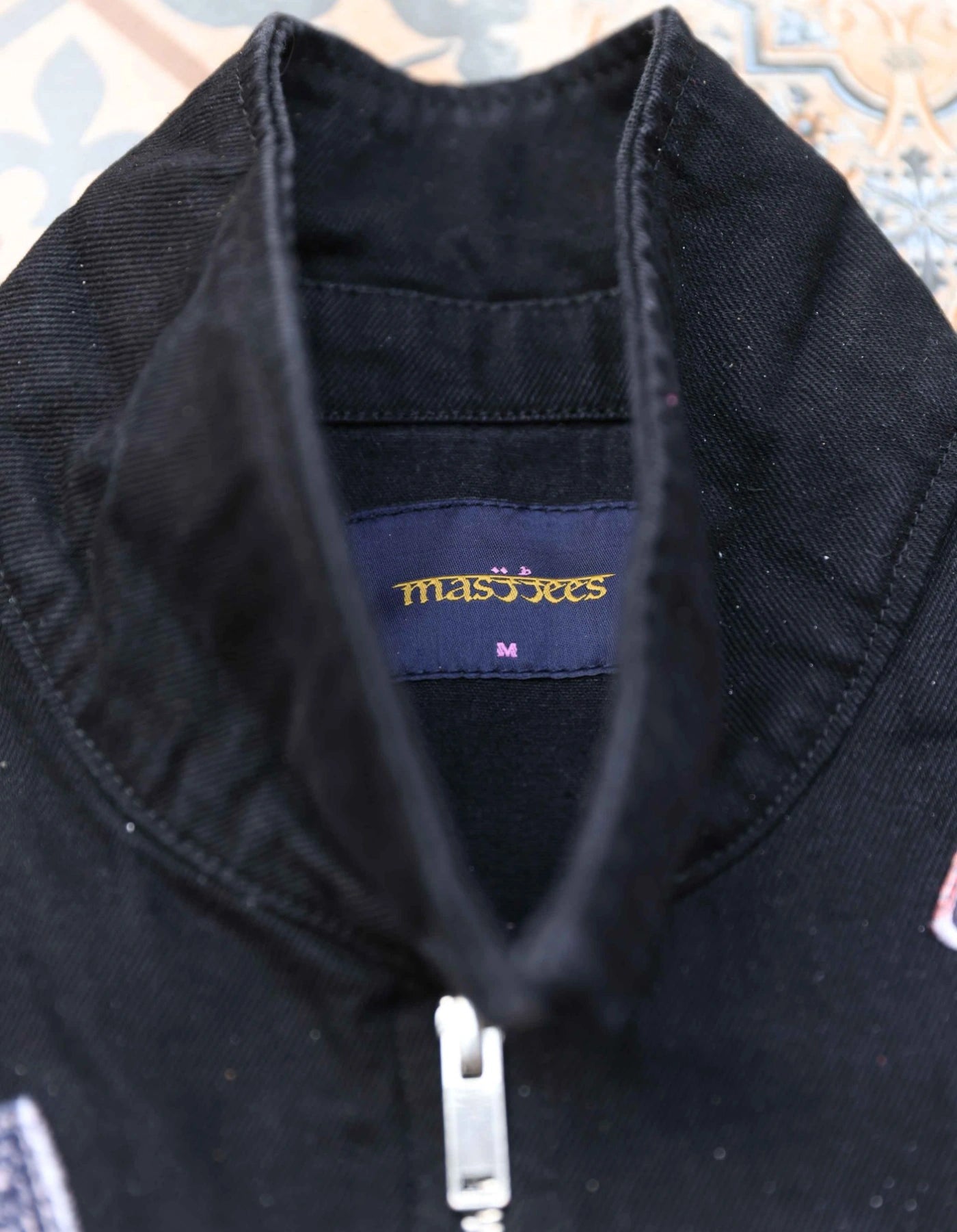 Close-up of a black jacket with a visible brand label on a patterned background