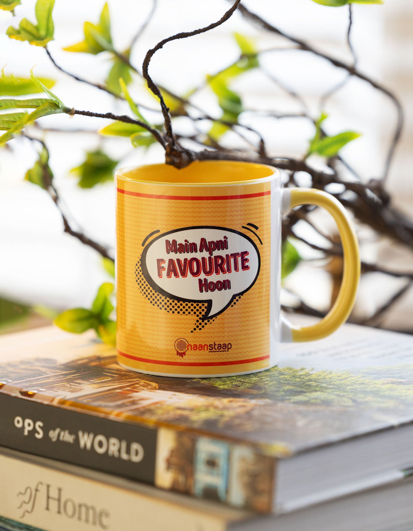 Yellow mug with text main apni favorite hoon against a blurred natural background